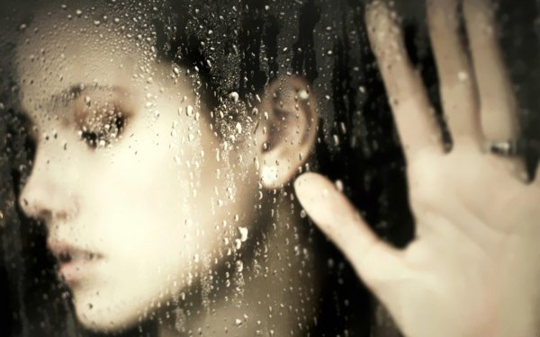 Девушка за стеклом с капельками