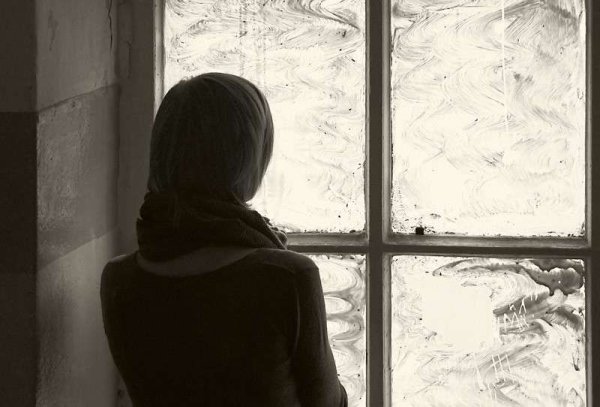 Женщина плачет у окна