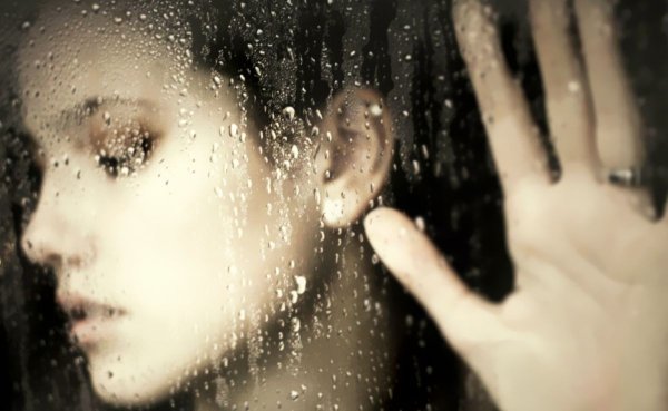 Девушка за стеклом с капельками