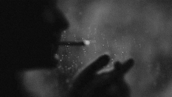 Мужчина с сигаретой в темноте