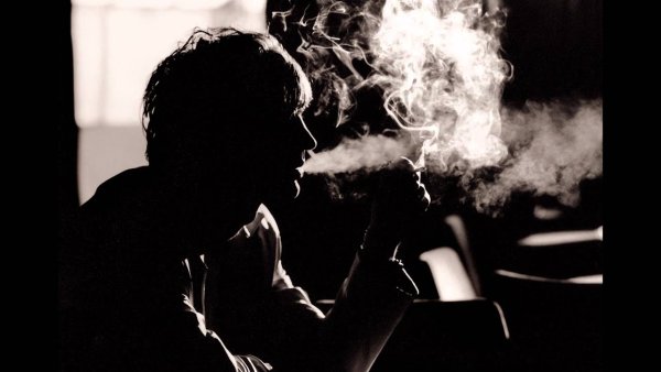 Мужчина с сигаретой в темноте