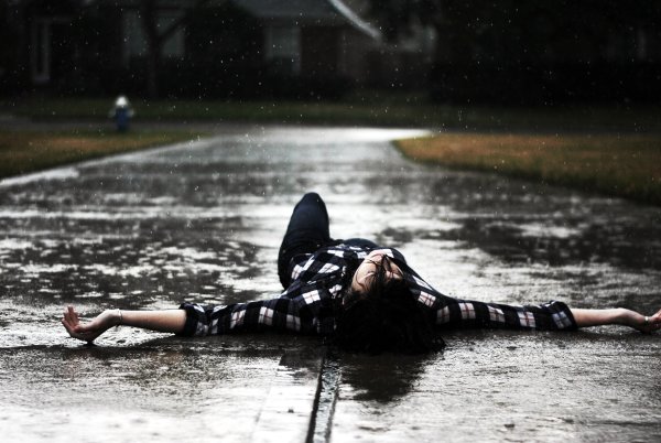 Девушка лежит на дороге под дождем