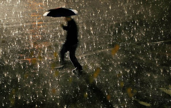 Мужчина с зонтом под дождем