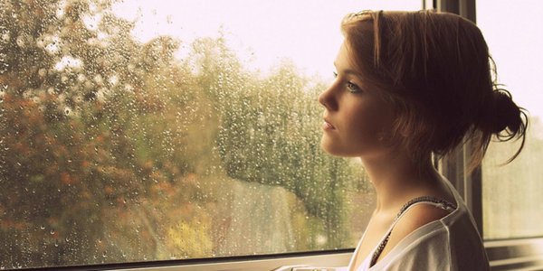 Девушка грустит у окна