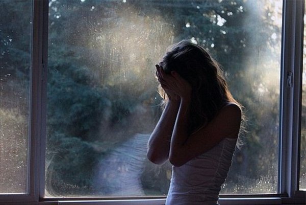 Девушка грустит у окна