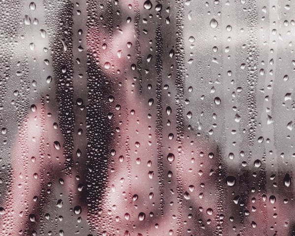 Девушка за стеклом с капельками