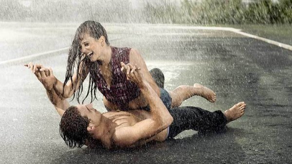 Парень лежит на асфальте под дождем