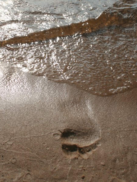 Следы на песке смывает водой