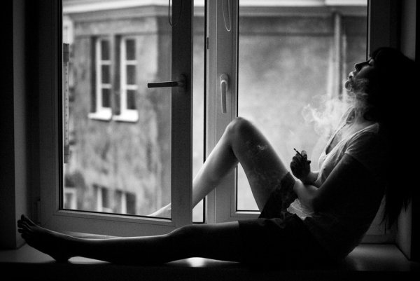 Девушка курит у окна