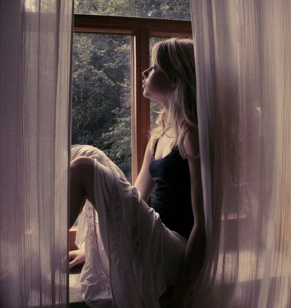 Девушка грустит у окна