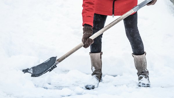 Женщина убирает снег лопатой