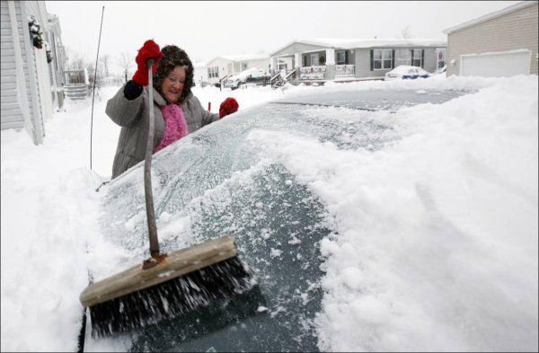 Девушка чистит машину от снега