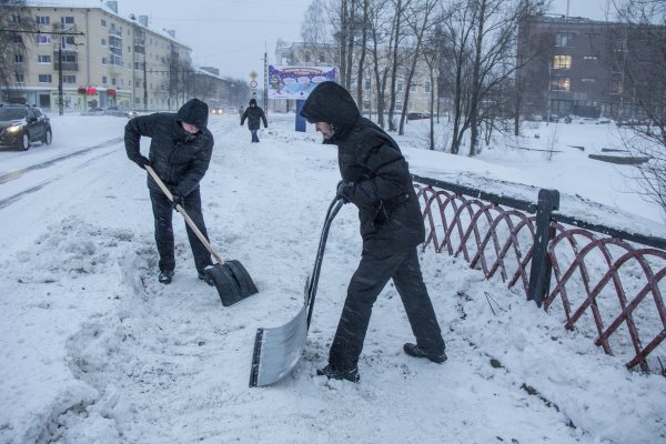 Убирает снег лопатой