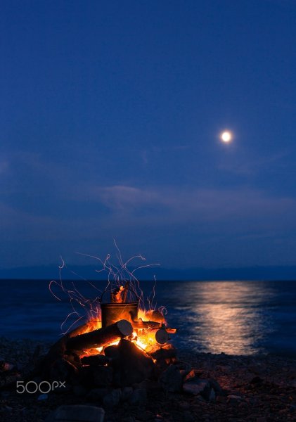 Костер на берегу моря ночью