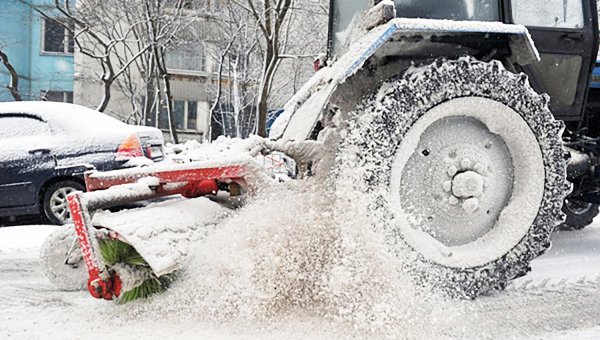 Трактор убирает снег во дворе