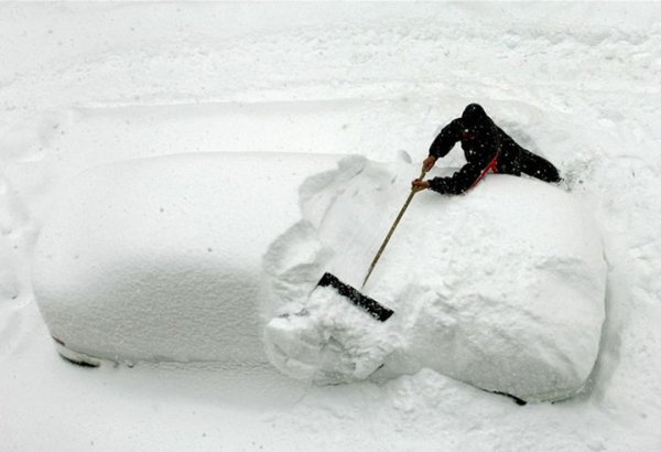 Откапывает машину из снега