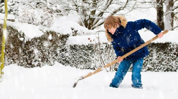 Зимой ребенок убирает снег