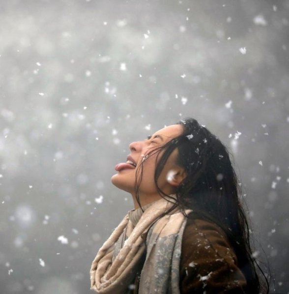 Девушка ловит снежинки ртом