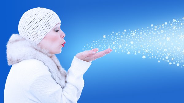 Девушка дует на снежинки