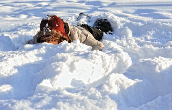 Девочка лежит на снегу в сугробе