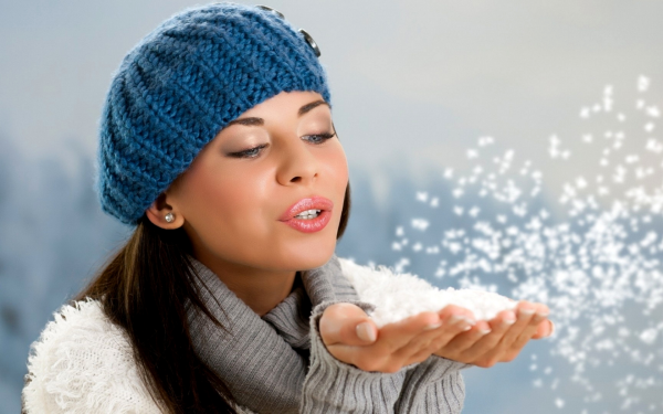 Девушка дует на снег