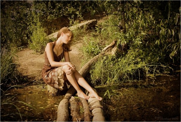 Девушка сидит на берегу реки