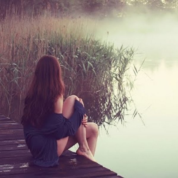 Девушка сидит у озера