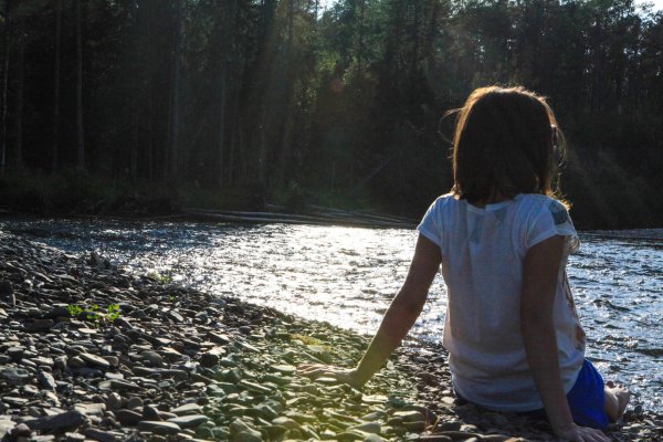 Девушка у реки со спины