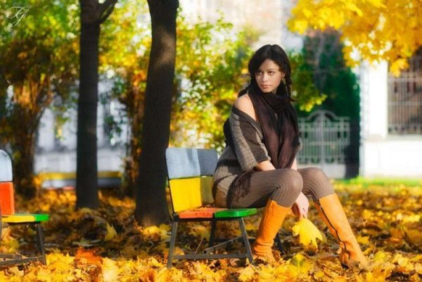 Женщина в парке на скамейке осенью