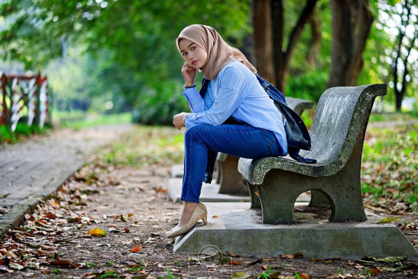 Девушка сидит на лавочке в парке