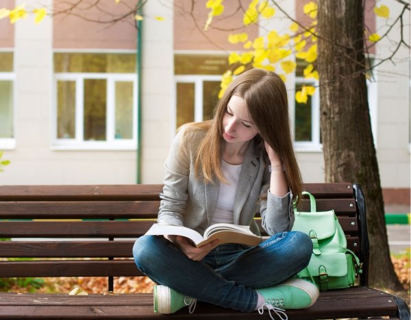 Девушка с книгой на скамейке в парке