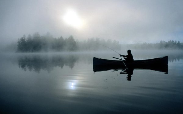 Рыбак в лодке на озере