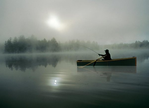 Рыбак в лодке на озере