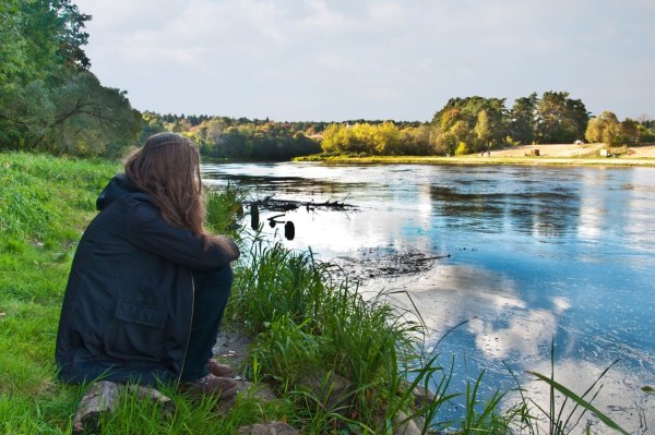 Девушка сидит у реки