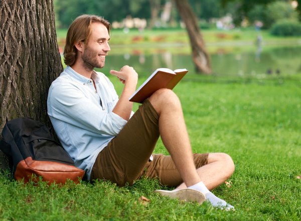 Мужчина читает книгу в парке