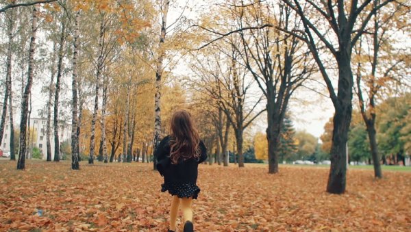 Девушка в осеннем парке со спины