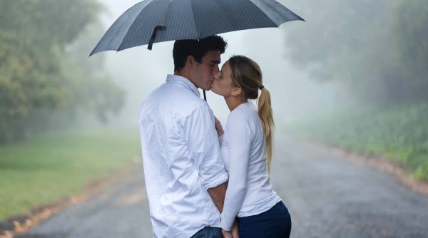 Пара идет под руку под зонтом