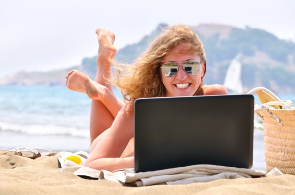 Человек лежащий на пляже с ноутбуком