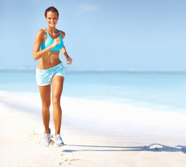 Спортивная девушка бежит по пляжу