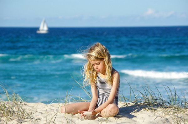 Девочка сидит на берегу