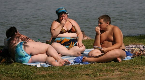 Полные люди на пляже