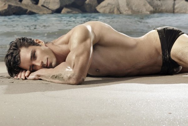 Красивый мужчина лежит на пляже