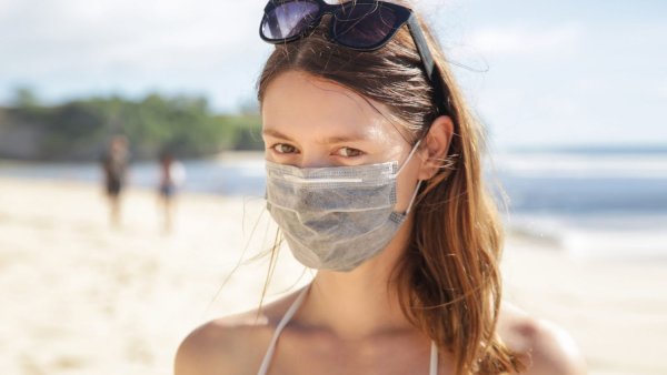 Девушка в медицинской маске на пляже