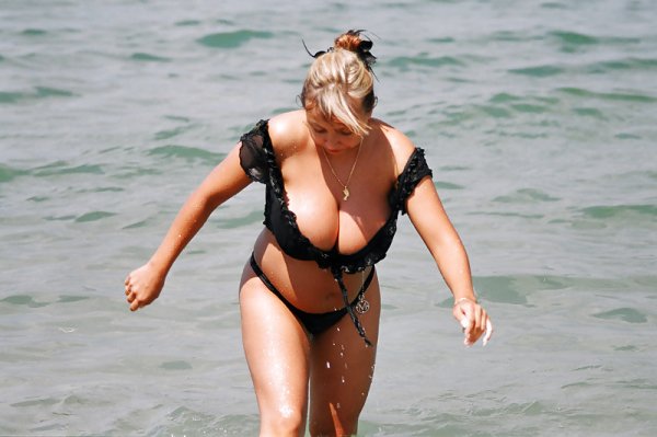 Девушка с большой грудью в купальнике на пляже.