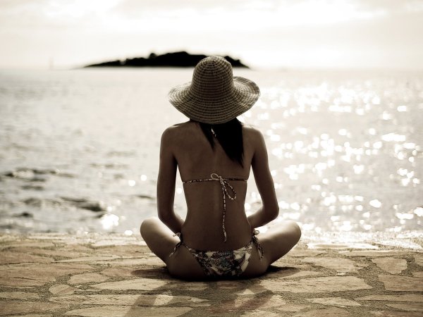 Девушка в шляпе на пляже со спины