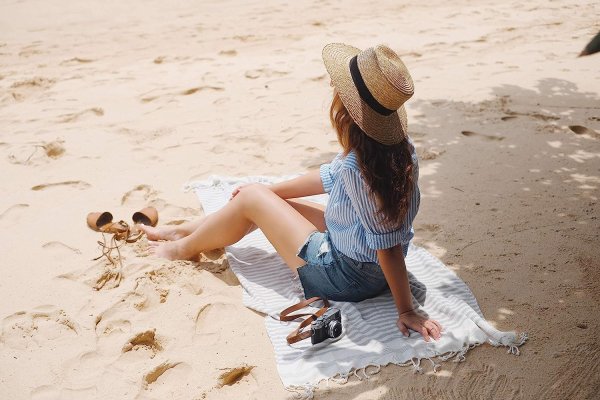 Девушка шляпа сидит пляж